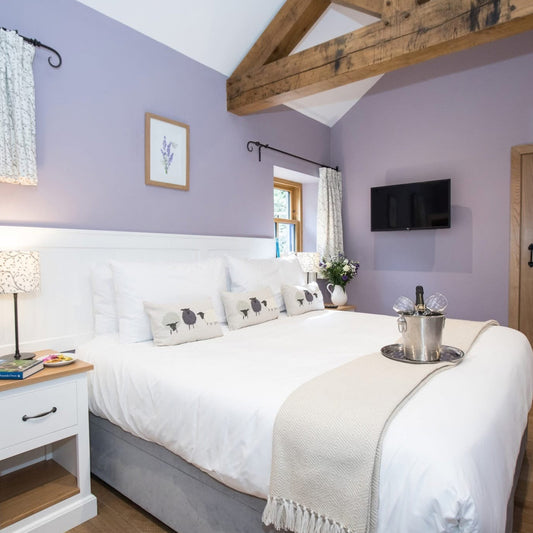 Charming en-suite bedroom with vaulted ceiling and lavender walls at Midlife Blush retreat

